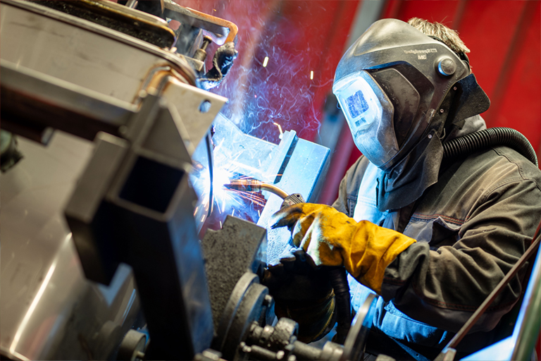 Ein Mitarbeiter der RTA schweißt mit dem MIG, MAG und WIG-Verfahren präzise ein dünnwandiges Metallteil.