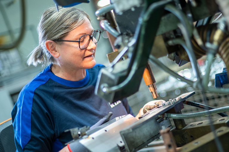 Eine Mitarbeiterin in der Metallbearbeitung der RTA GmbH, ehemals Rothtechnik Austria, bearbeitet Metallteile mittels punktschweißen.