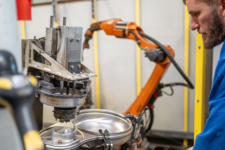 Ein Mitarbeiter der RTA GmbH arbeitet an einem Schweißroboter-Arbeitsplatz